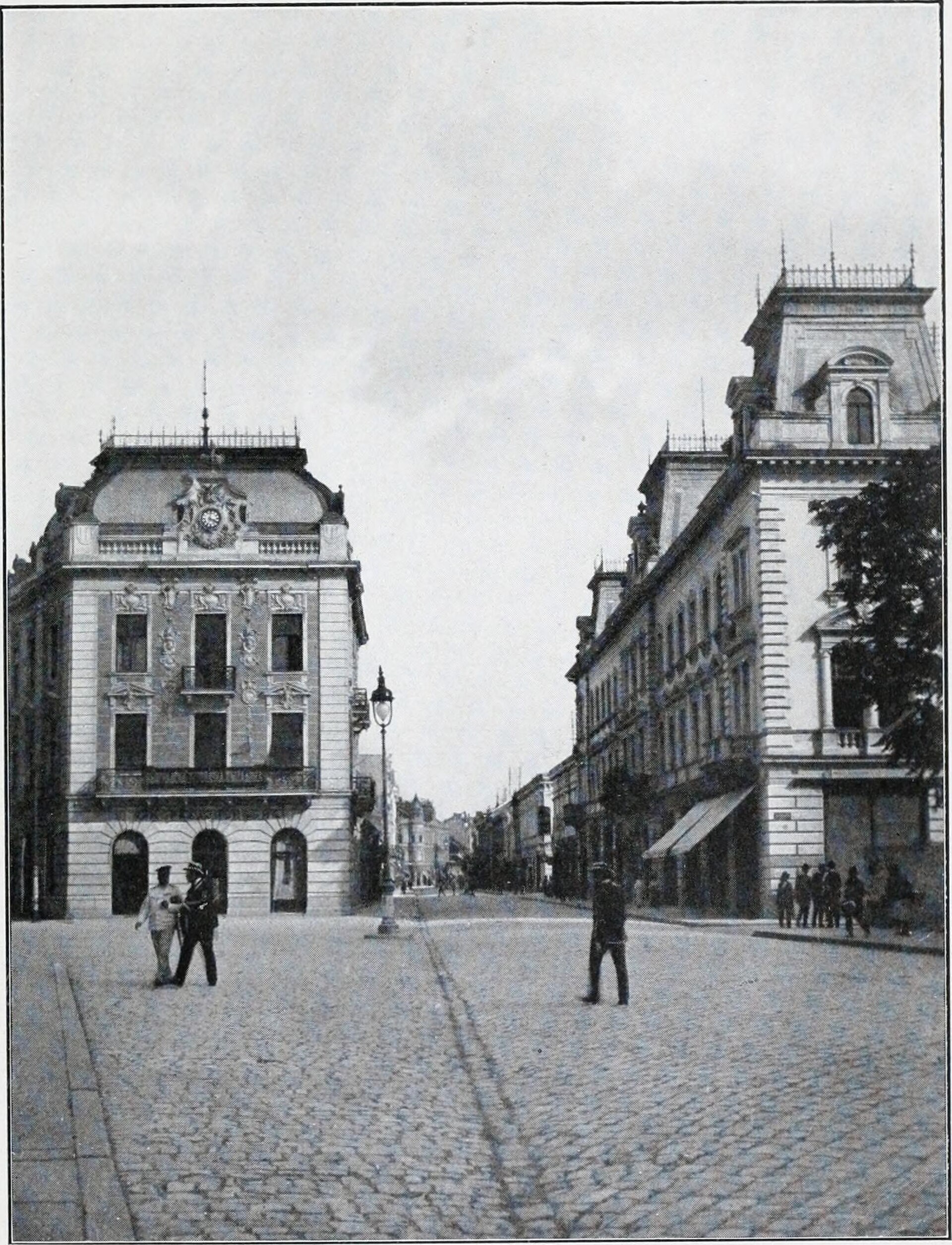 Cobblestone street between ornate historic buildings with pedestrians and a clear open sky