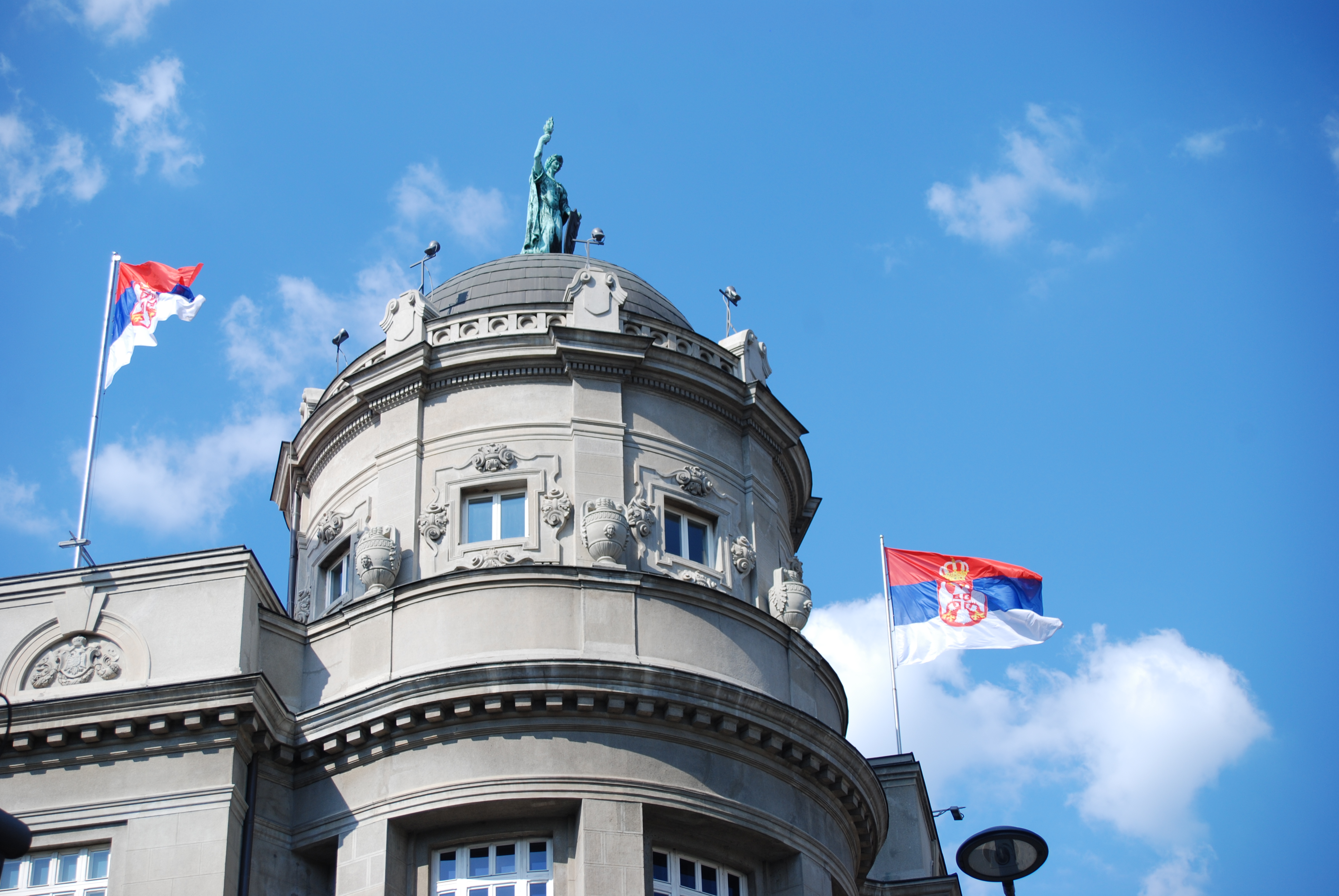 Domed facade with Serbian flags and a statue atop the Academy of Sciences and Arts in Belgrade