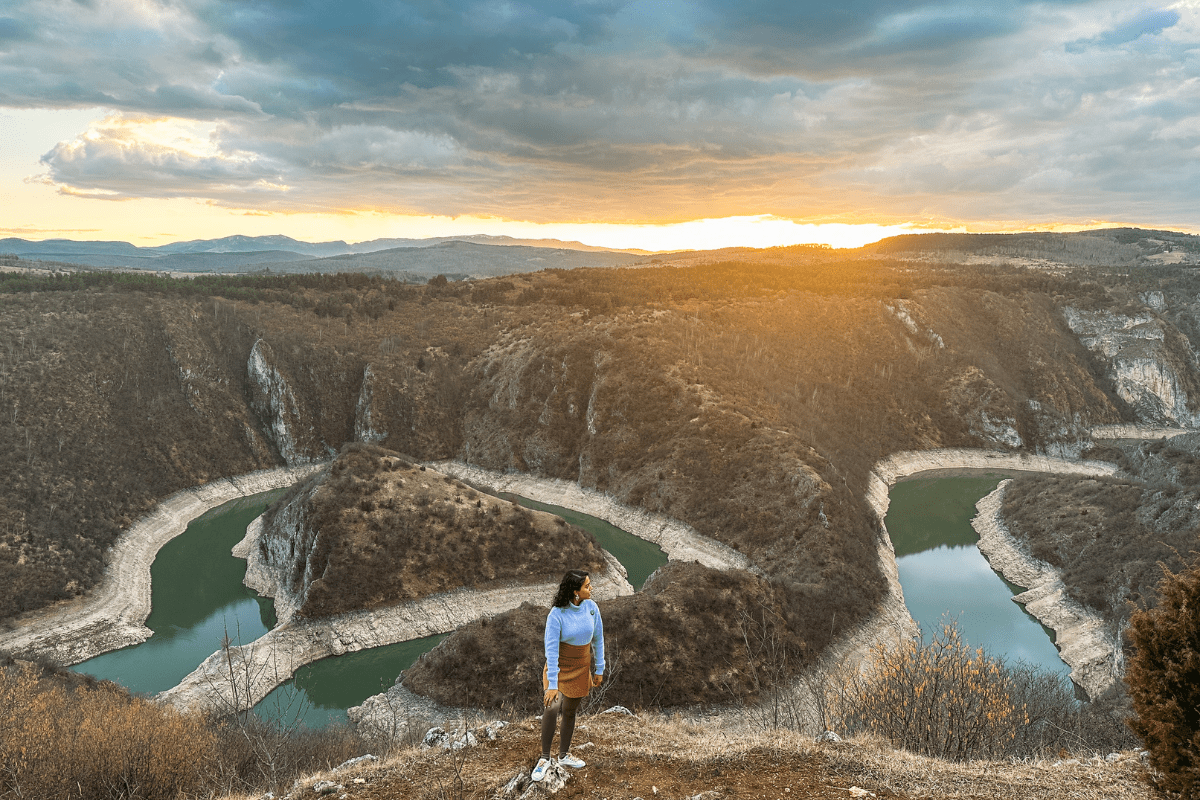 Person standing above winding river bends in Uvac Canyon, Western Serbia, at sunset