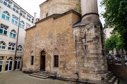 Stone exterior of Bajrakli Mosque with arched windows and a minaret in Belgrade
