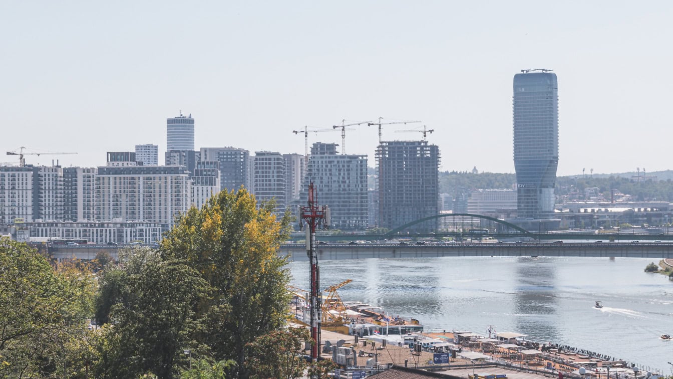 High-rise towers, cranes, and a bridge along the Sava River at Belgrade Waterfront