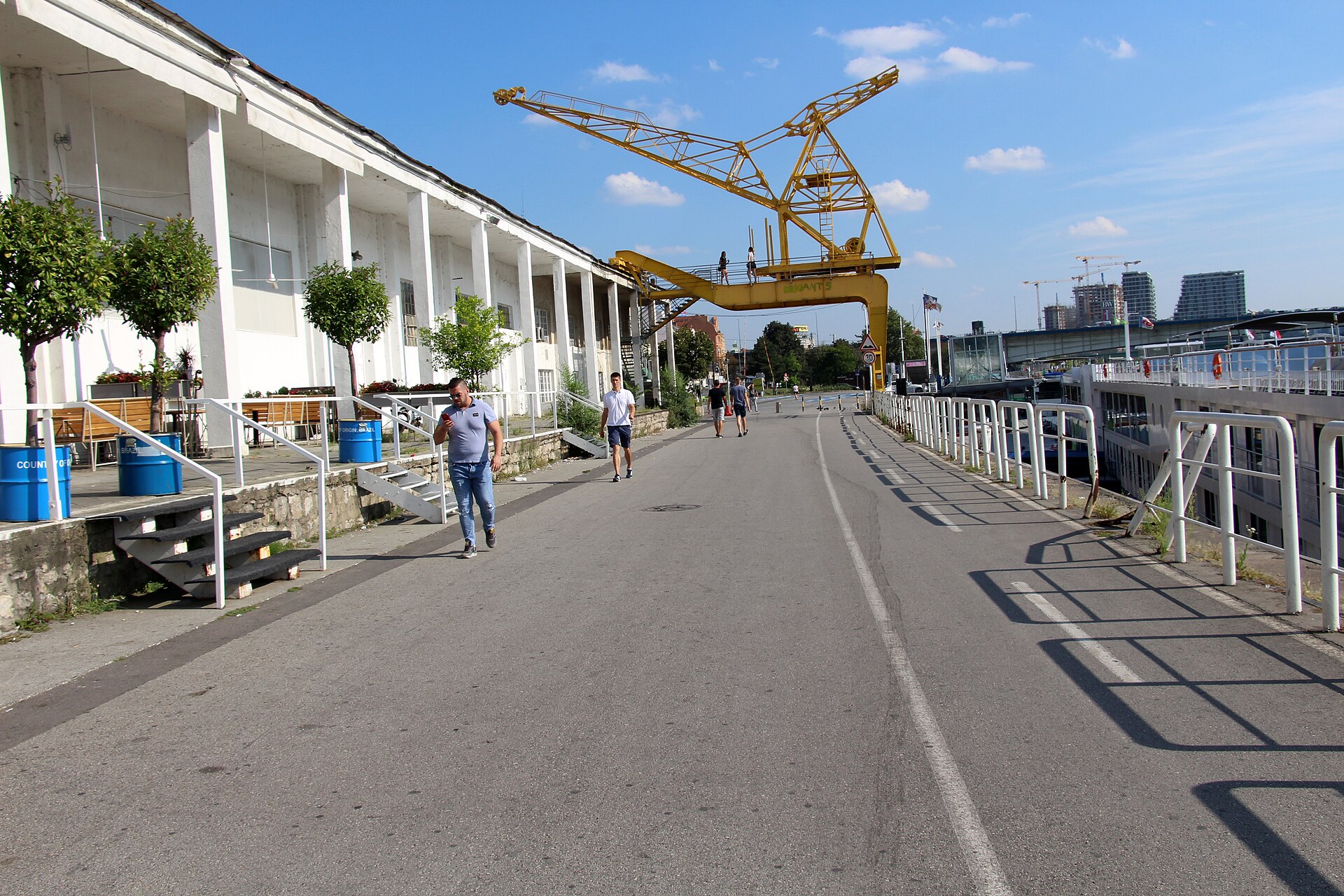 Waterfront promenade with a yellow industrial crane and white colonnade at Beton Hala, Belgrade