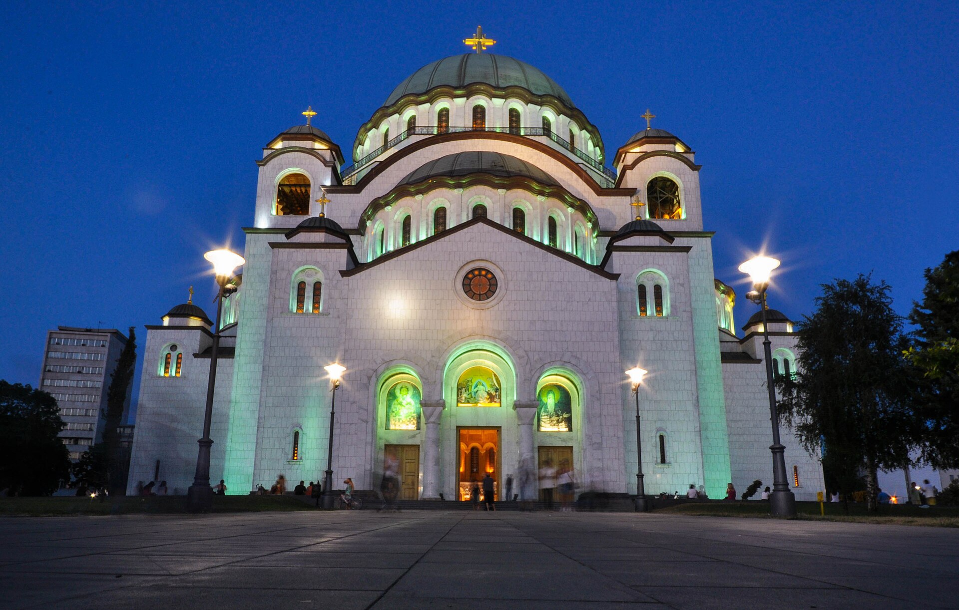Cathedral of Saint Sava lit at night in Belgrade with domes, crosses, and a wide plaza