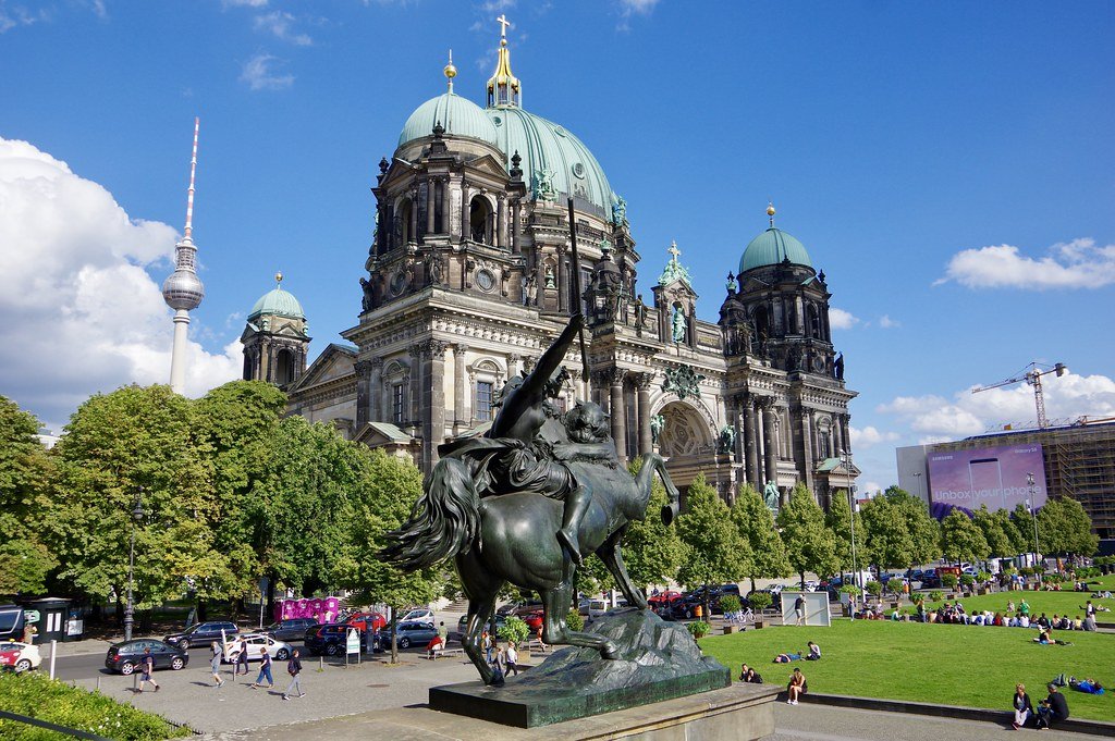 Domed cathedral behind an equestrian statue, with trees and a tower in the background