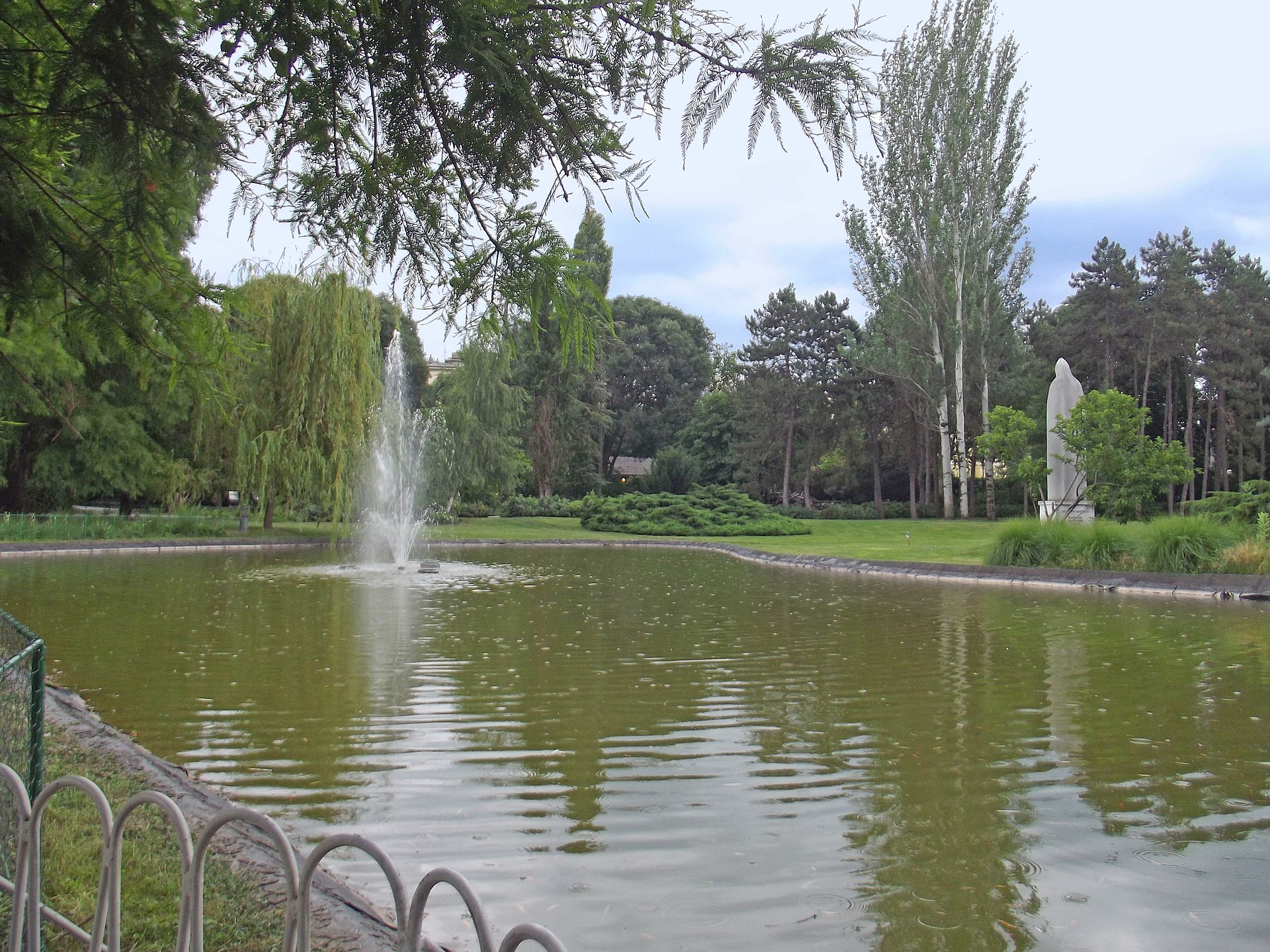 Fountain in a pond surrounded by trees and grass in Dunavski Park, Novi Sad