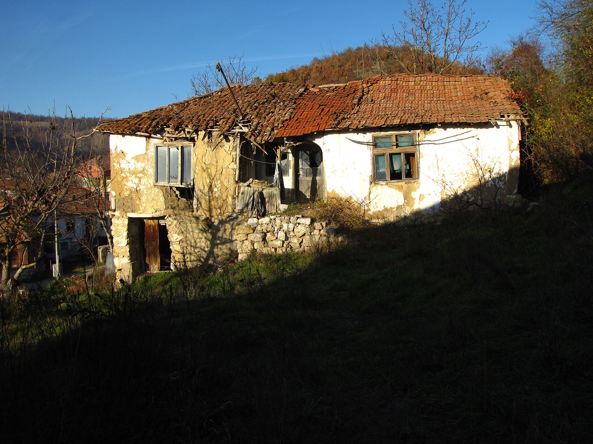 Weathered hillside house with a damaged tiled roof in Eastern Serbia