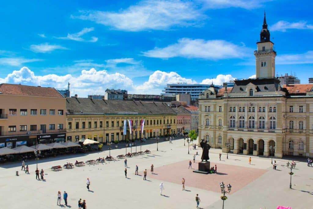 Freedom Square in Novi Sad with city hall, central statue, and people across the open plaza
