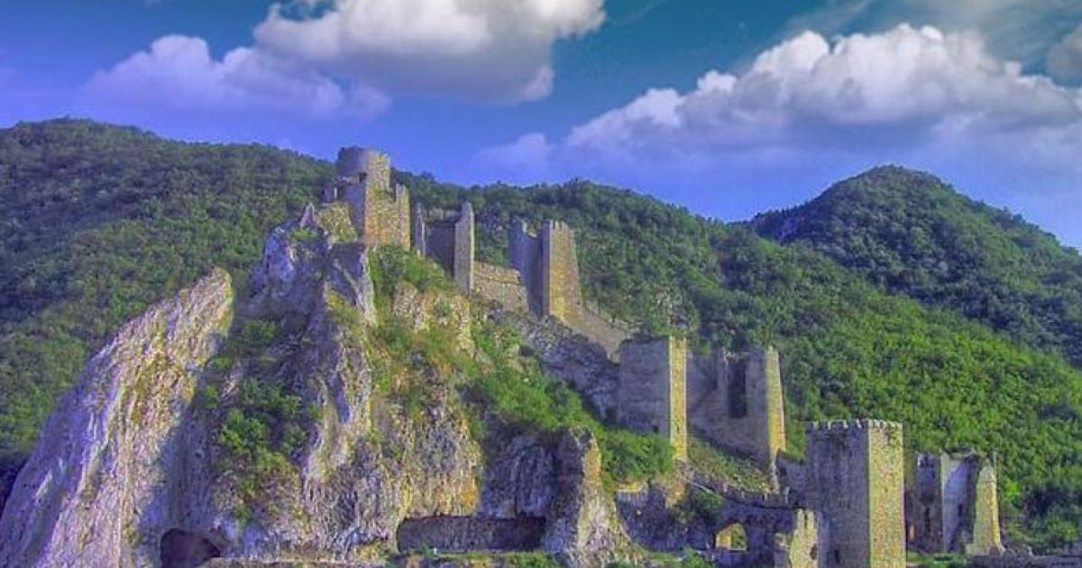 Golubac Fortress towers and walls on a steep cliff above forested hills