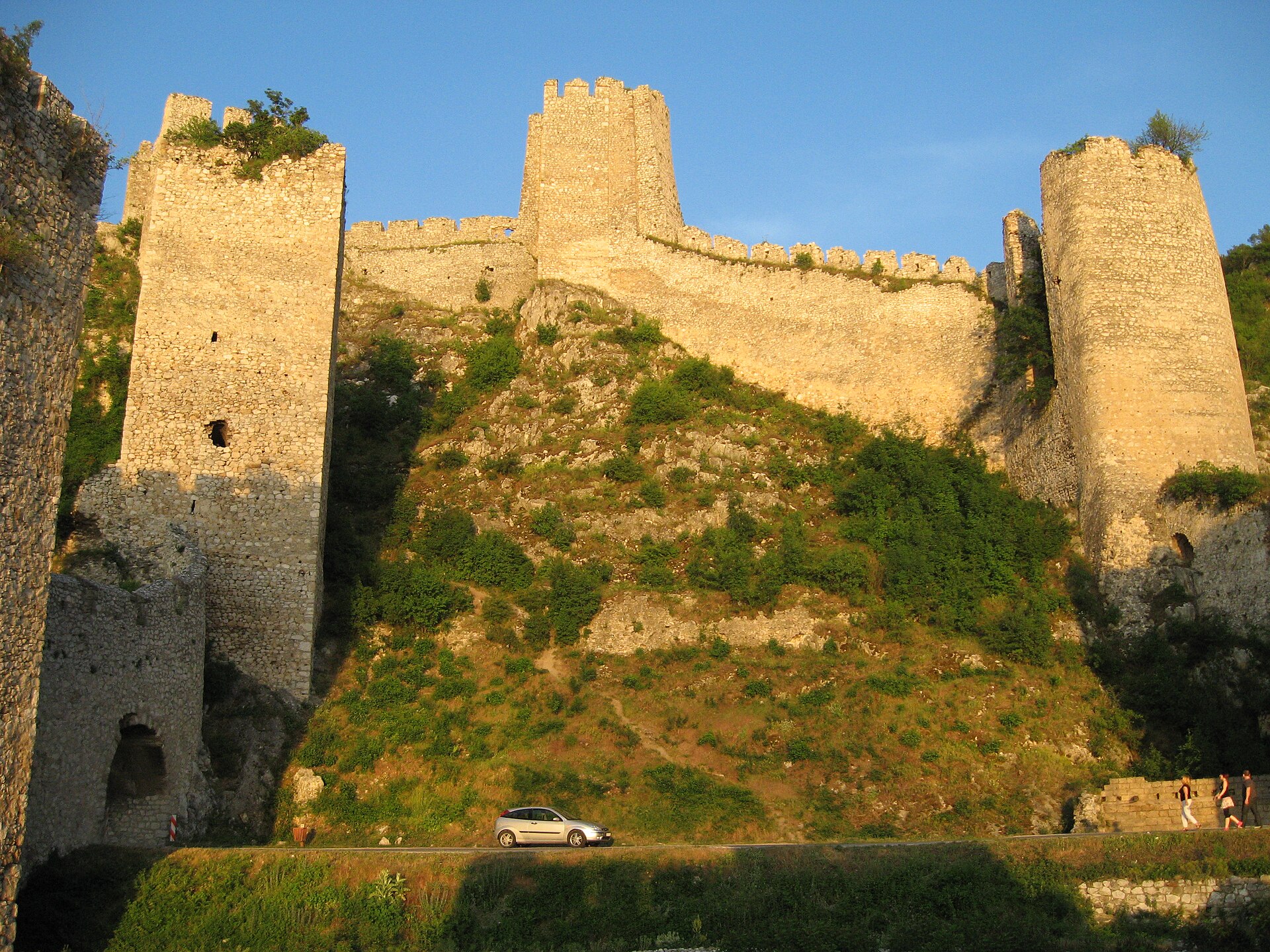 Stone fortress walls and towers rising above a steep hillside at Golubac Fortress