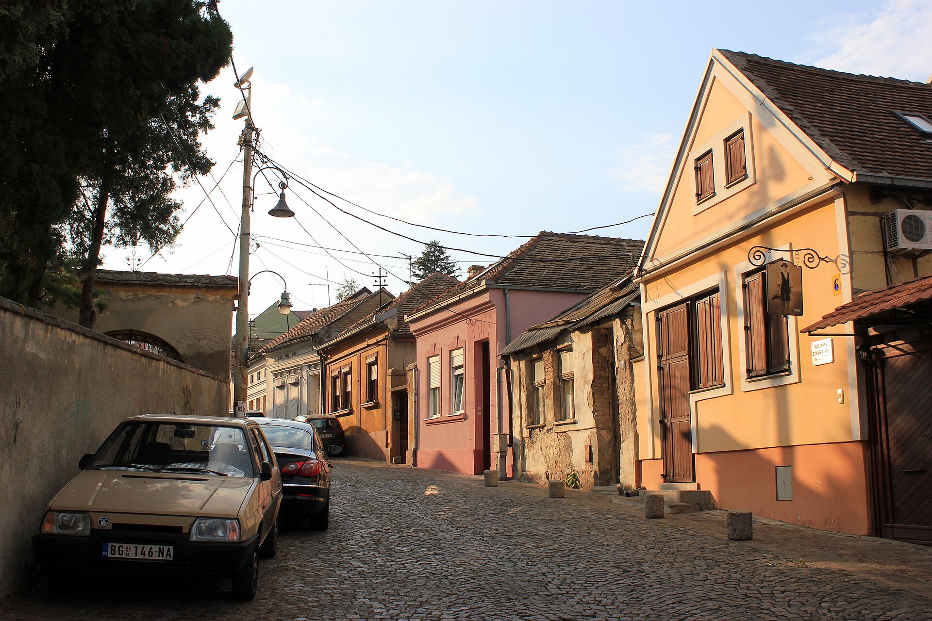 Cobblestone street with colorful old houses and parked cars in Zemun