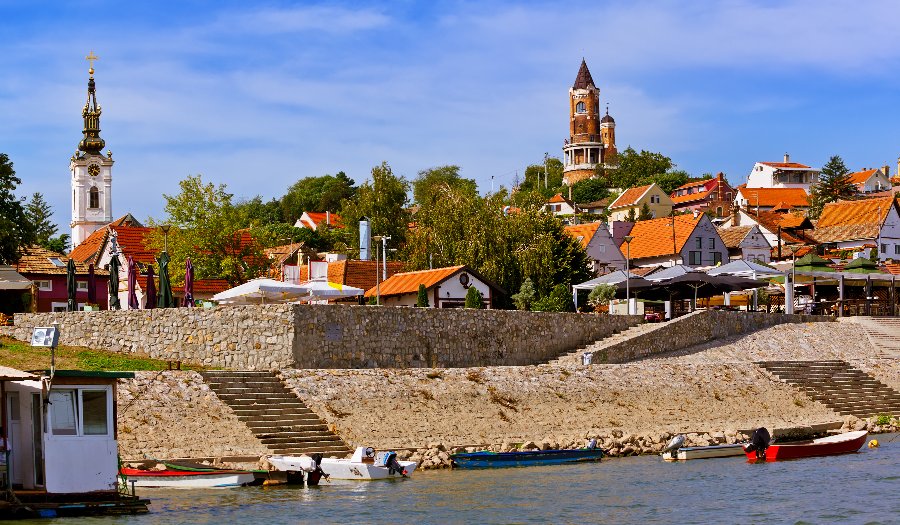Zemun riverside with stone embankment, colorful rooftops, and historic church tower above the Danube