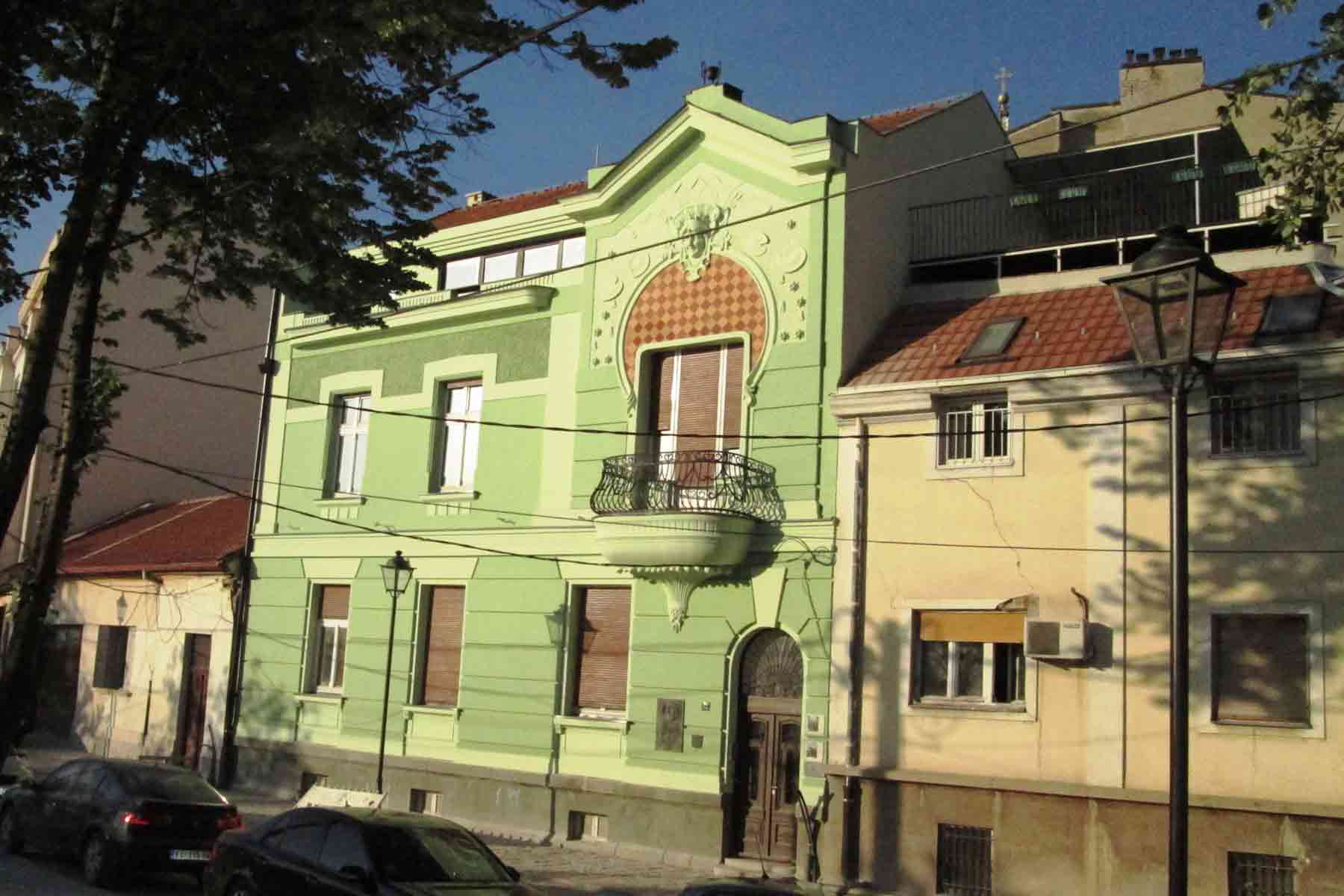 Pastel green historic house with ornate balcony details on a street in Kosančićev Venac, Belgrade