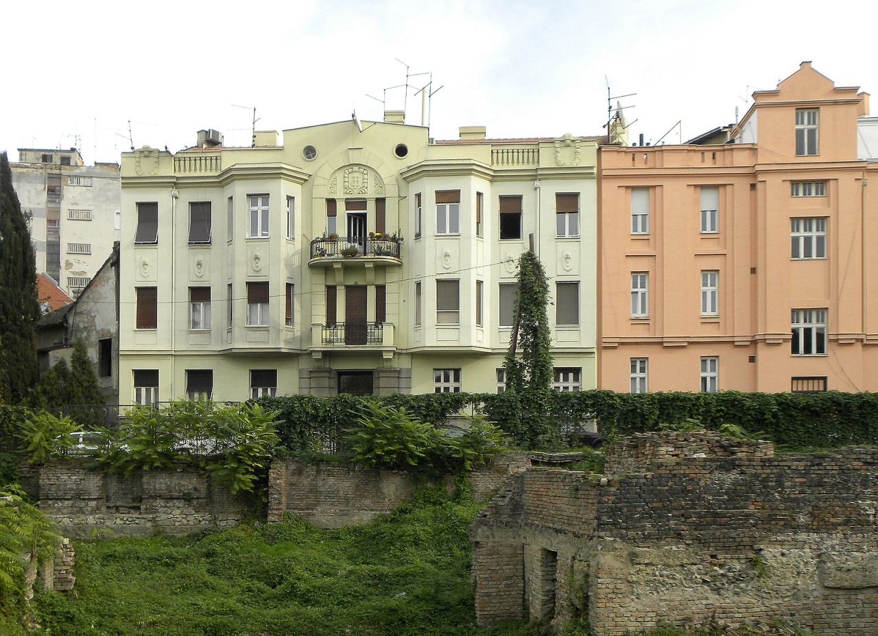 Pastel residential buildings rise above low brick ruins and greenery in Kosančićev Venac, Belgrade