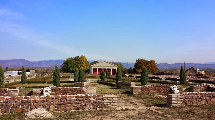Stone ruins and paths at Mediana in Niš, with a small shelter and hills in the background
