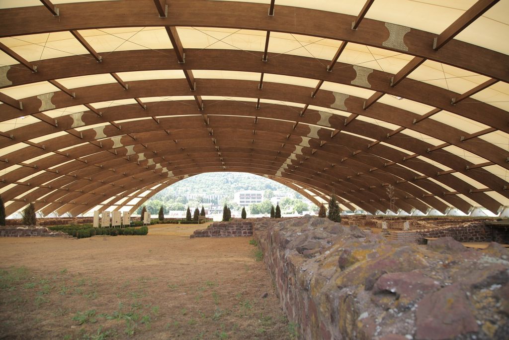 Archaeological ruins under a curved protective canopy at Mediana in Niš