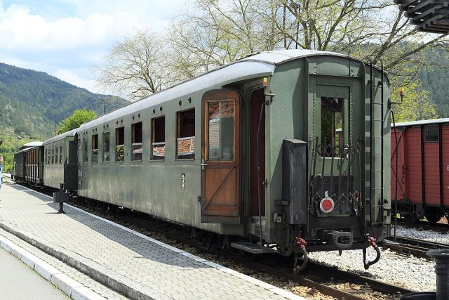 Vintage green railway carriage beside a platform in Western Serbia with mountains in the background