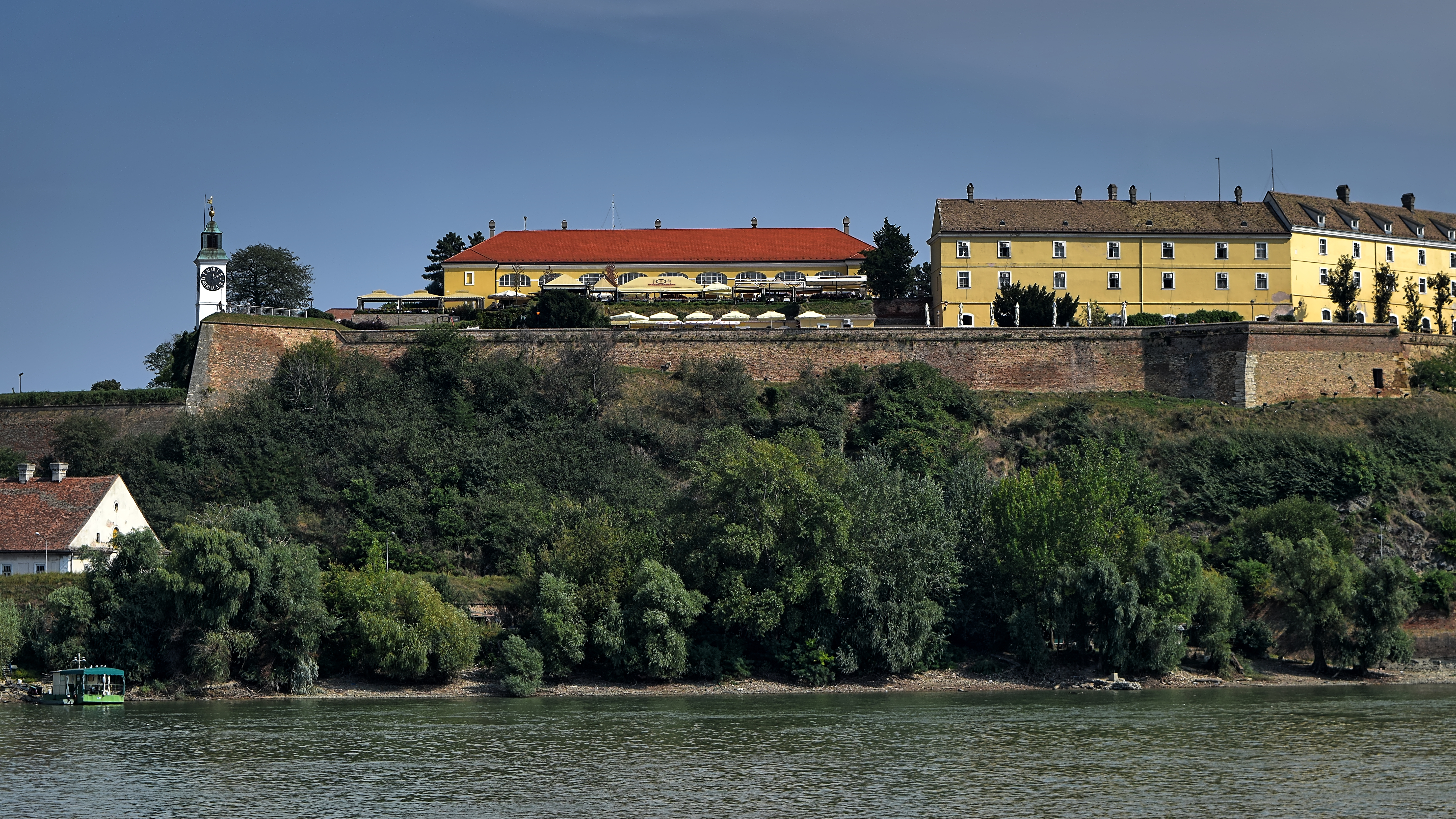 Petrovaradin Fortress with a clock tower and yellow buildings above the Danube in Novi Sad