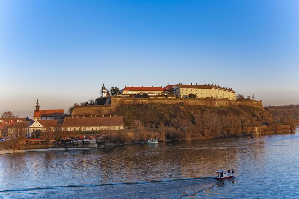 Petrovaradin Fortress overlooking the Danube with hilltop buildings and a small boat on the river