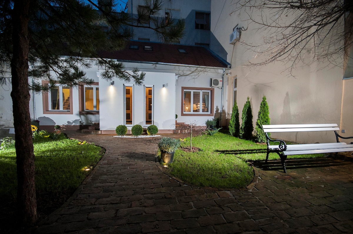 Paved courtyard with bench, shrubs, and lit windows at the Residence of Princess Ljubica in Belgrade