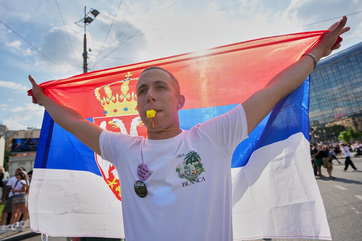 Man holding a Serbian flag wide open in a crowded street during Art Festivals