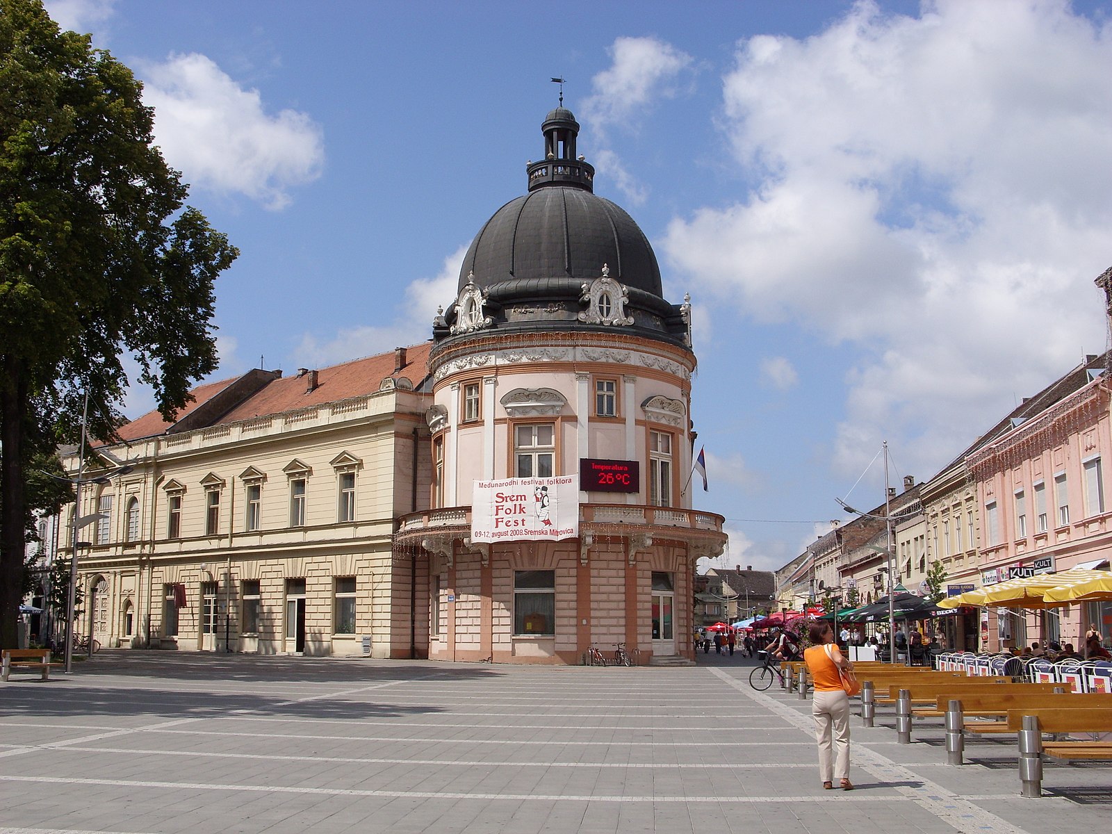 Domed historic building on a pedestrian square in Sremska Mitrovica with cafés and benches