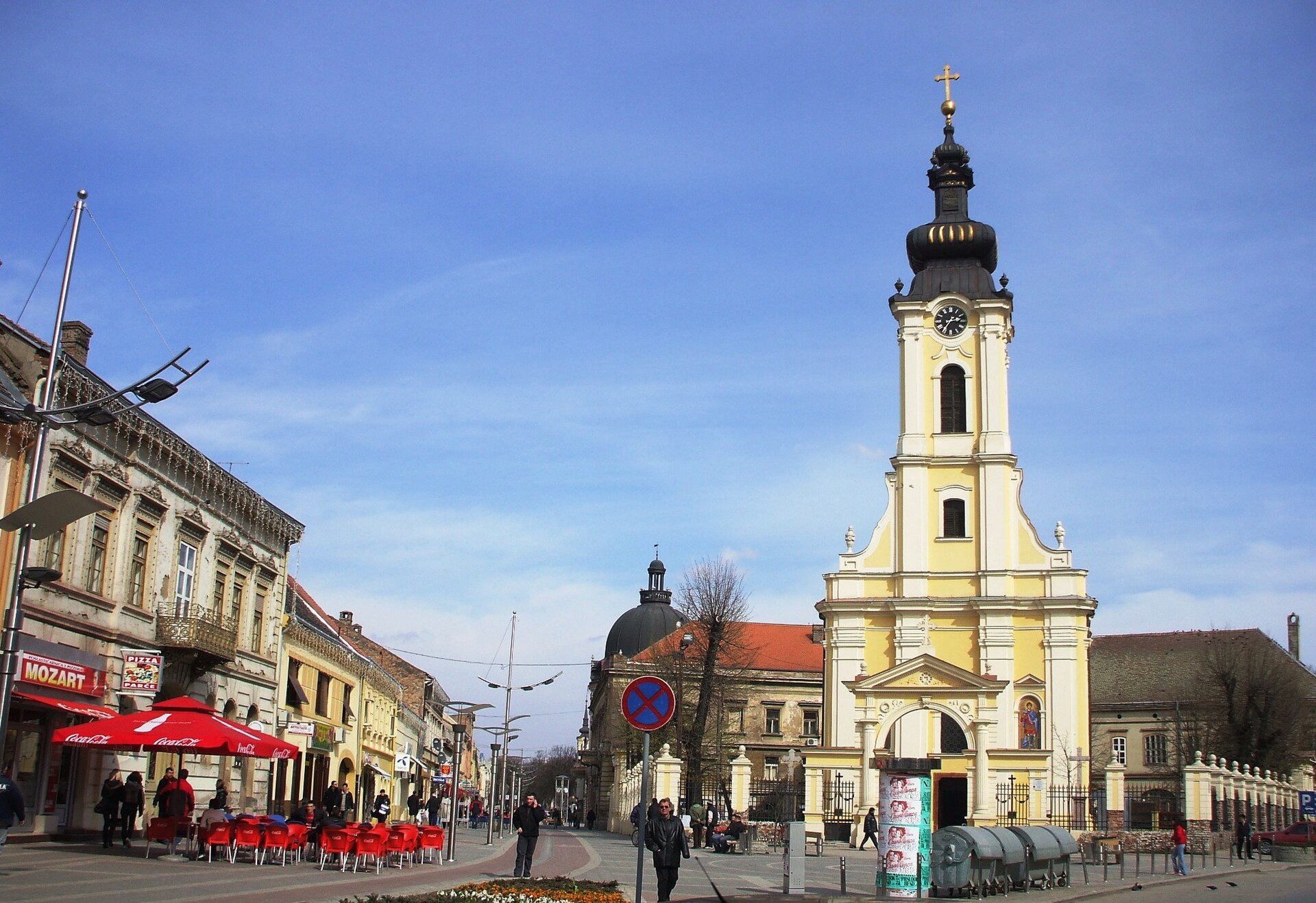 Church tower overlooking a pedestrian square with cafes and old buildings in Sremska Mitrovica