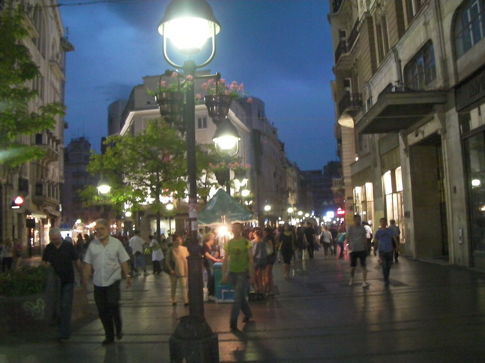 Crowded pedestrian street at dusk with glowing lampposts and shopfronts in Stari Grad, Belgrade