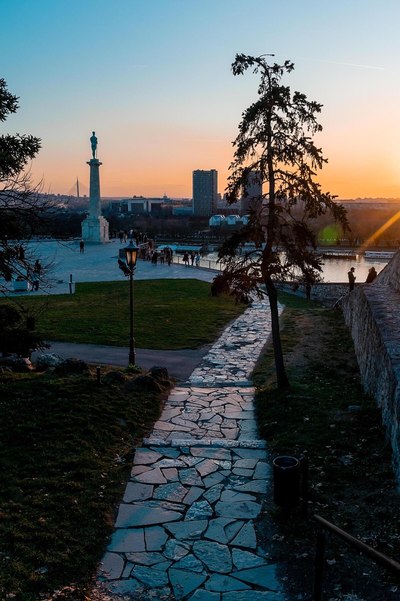Stone path in Stari Grad leads to a monument and river overlook at sunset