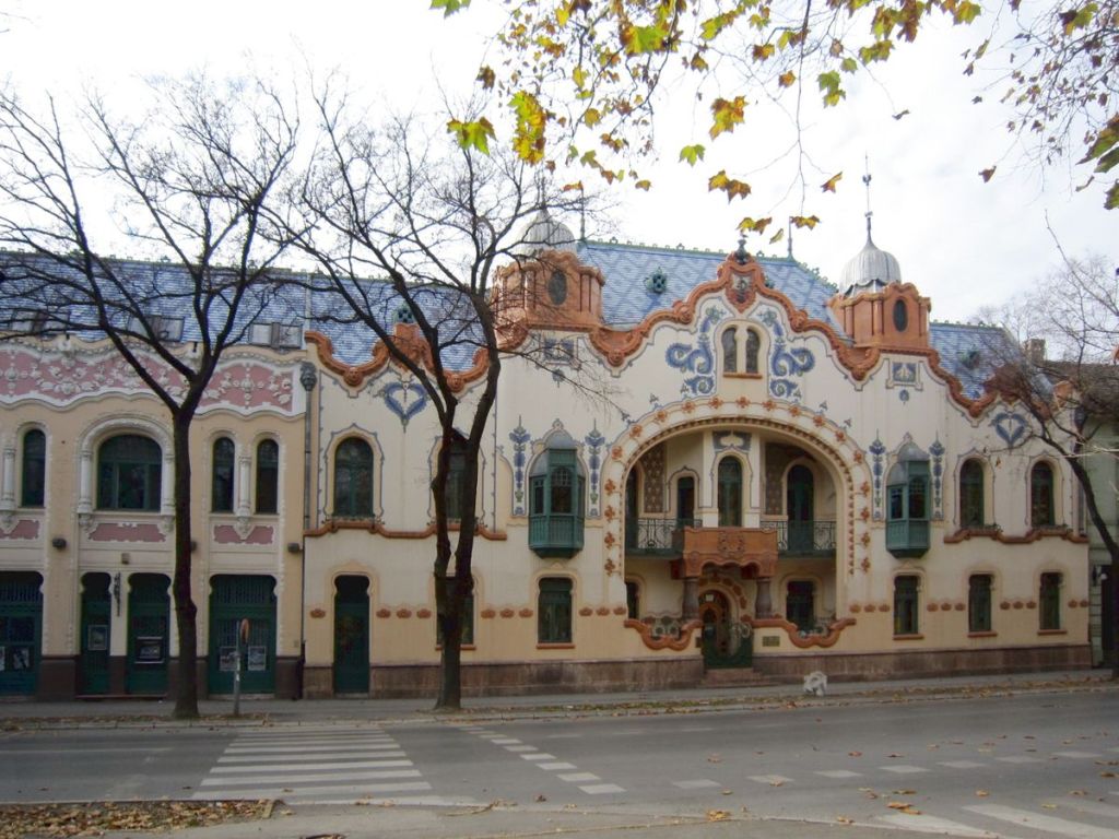 Ornate Art Nouveau building with curved facade and decorative windows on a street in Subotica