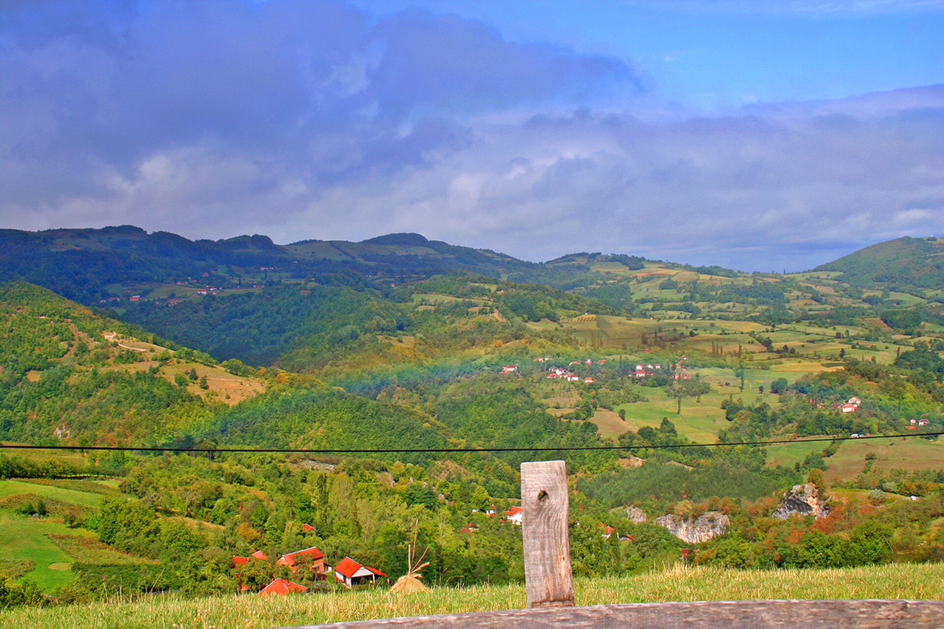 Rolling hills, scattered red-roofed houses, and patchwork fields in Tara Valley under cloudy skies