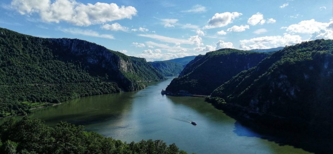Danube River winding through steep forested cliffs in Djerdap National Park, with a boat on the water