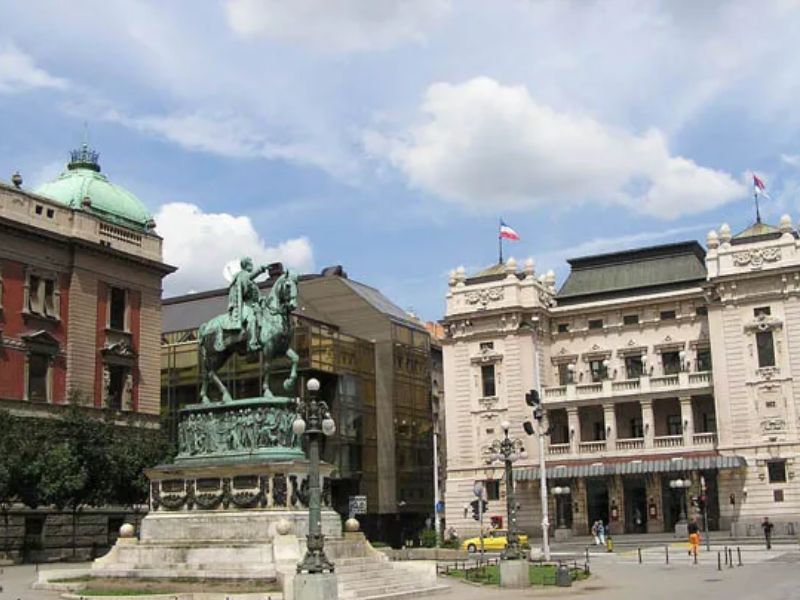 Equestrian statue in Trg Republike, Belgrade, with historic buildings and a cloudy sky