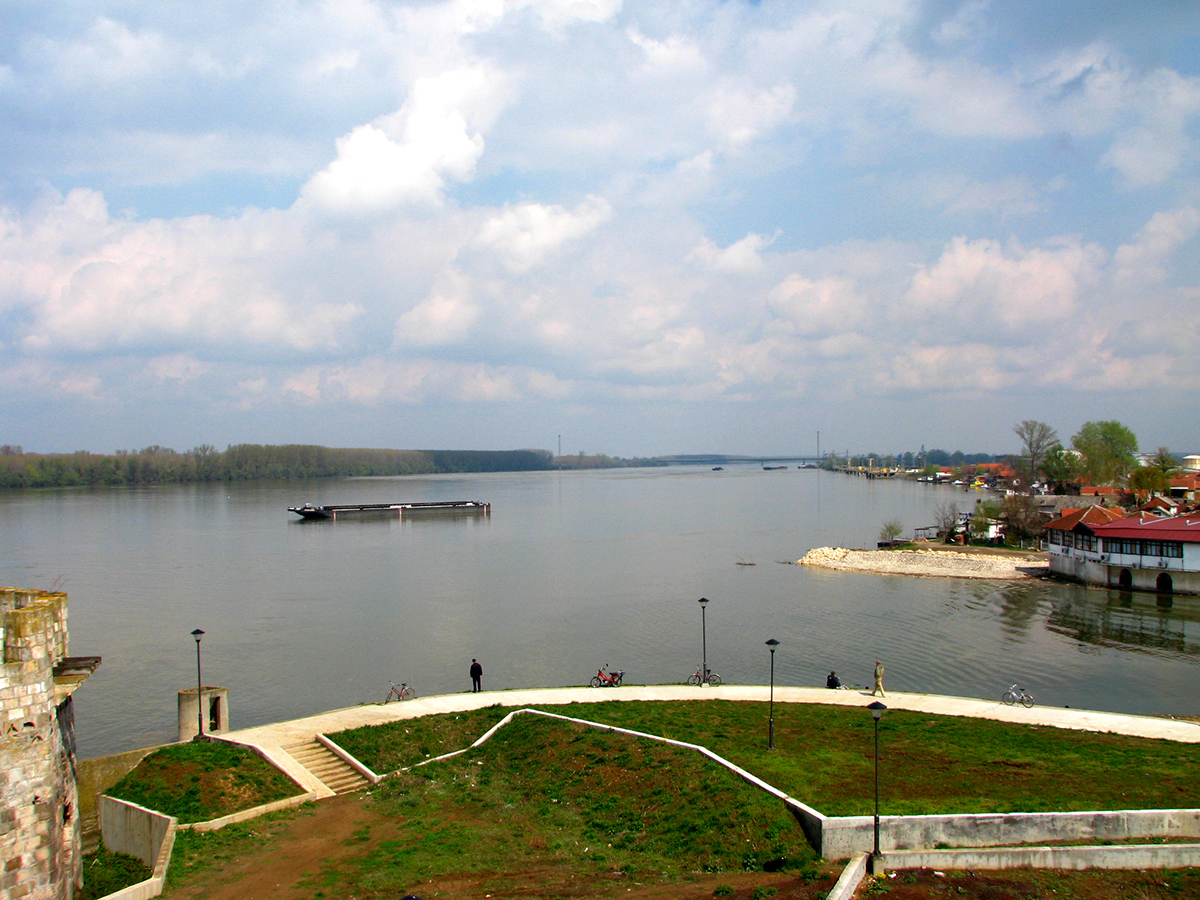 Danube River view from a grassy fortress terrace in Smederevo with paths, lamps, and distant boats