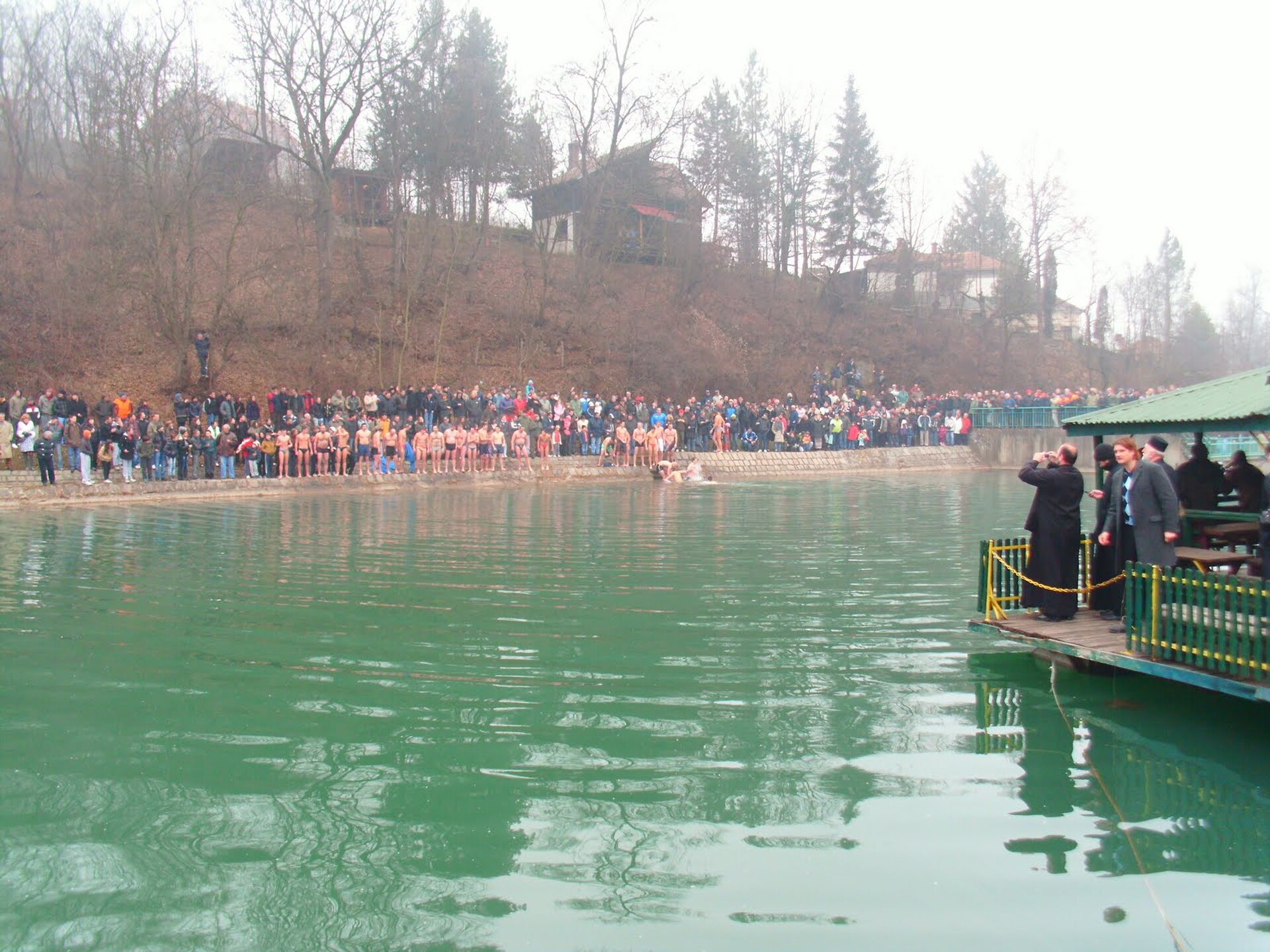 Crowd gathered around a green spring pool with swimmers in Valjevo