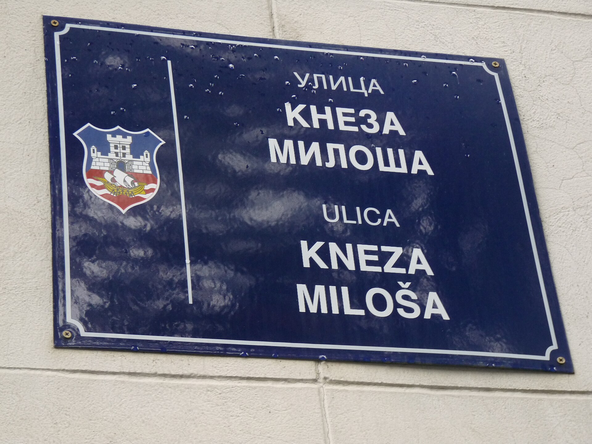 Blue street sign for Ulica Kneza Miloša mounted on a wall in Valjevo