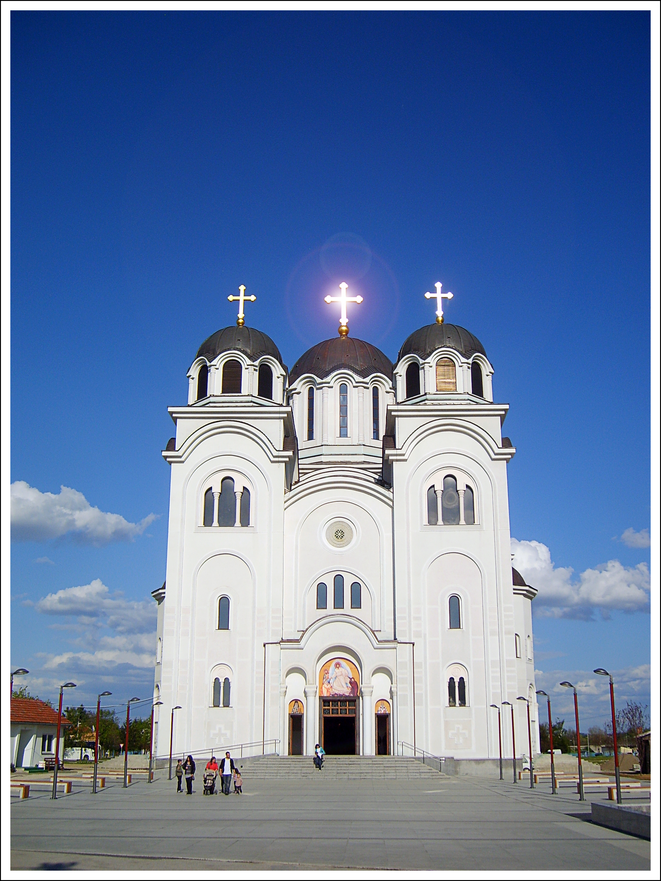 White Orthodox church with three domes and crosses in Valjevo under a clear blue sky