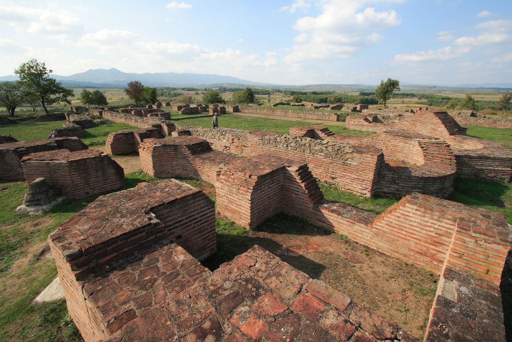 Brick ruins and foundation walls at the Vinča archaeological site near Belgrade, with fields and distant hills