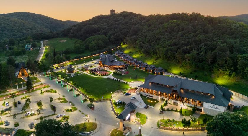 Illuminated spa resort complex beside forested hills in Vrdnik Spa at dusk