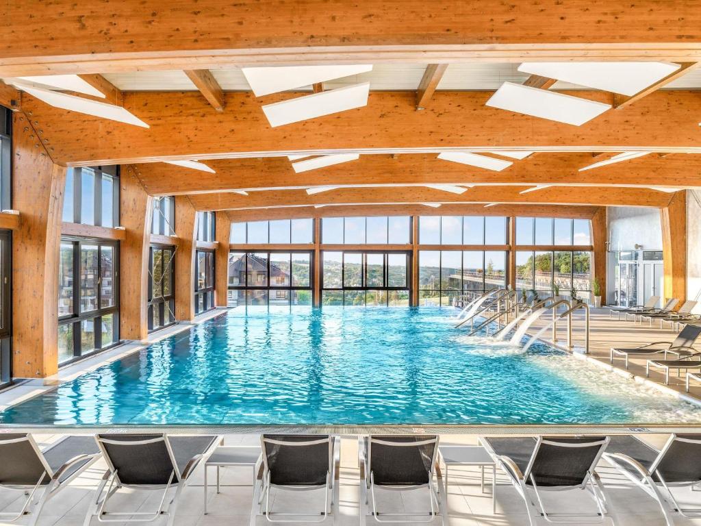 Indoor swimming pool with loungers, wooden ceiling, and large windows at Vrdnik Spa