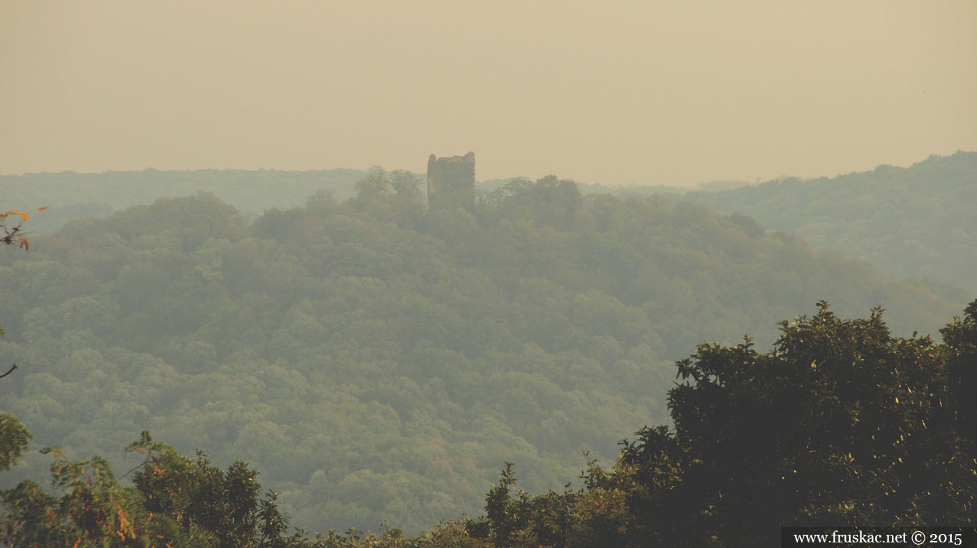 Ruined stone tower on a forested hill above hazy green slopes near Vrdnik Spa