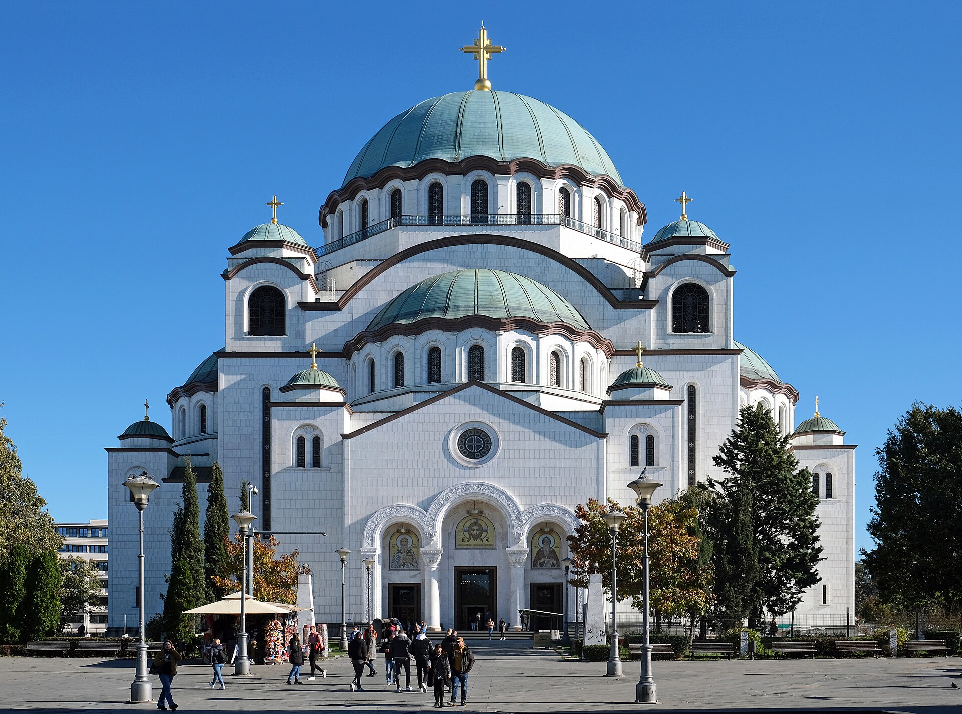 Large Orthodox cathedral with green domes and gold crosses in a square in Western Serbia