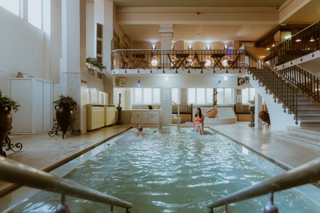 Indoor thermal pool with guests, stairs, and balcony seating in Western Serbia