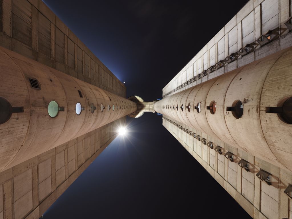 Low-angle view of two concrete towers connected by a bridge in Western Serbia at night