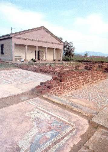 Mosaic floor fragments and stone ruins beside a reconstructed building at Mediana in Niš