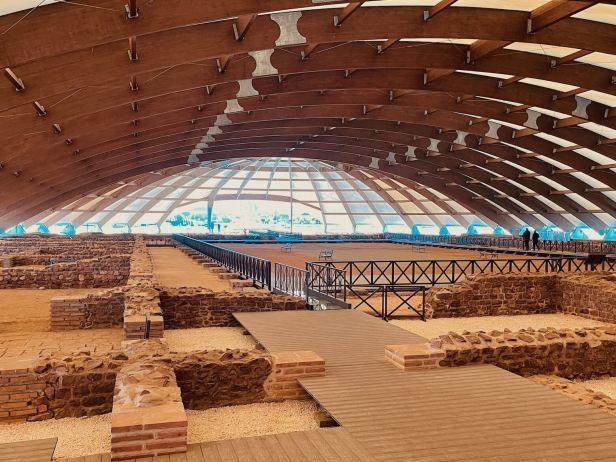 Ruins and raised walkways beneath a large curved canopy at Mediana in Niš